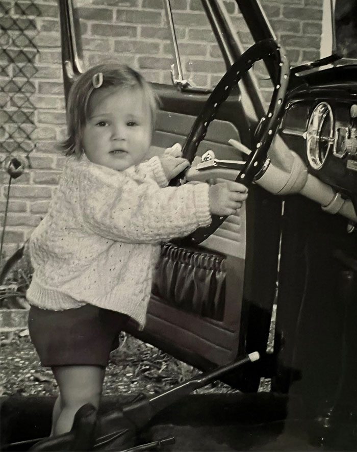 Suzette Moerman als peuter achter het stuur van een auto